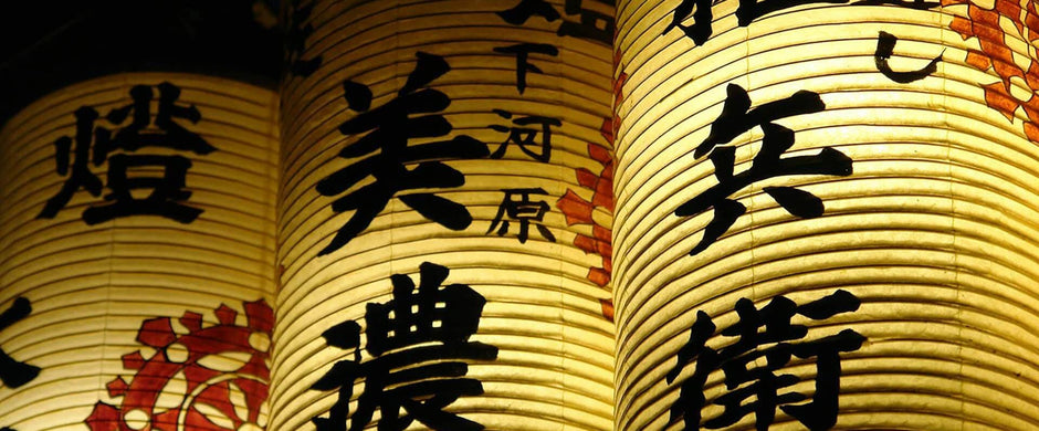 Three glowing Japanese paper lanterns with black calligraphy.