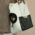 Load image into Gallery viewer, Cat safely peeking out of the Oatmilk white Nomad Cat Carrier Tote worn by owner.
