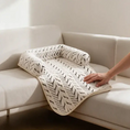 Load image into Gallery viewer, Hand smoothing The Sumi Lounger cat couch protector mat with raised bolsters on a cream sofa
