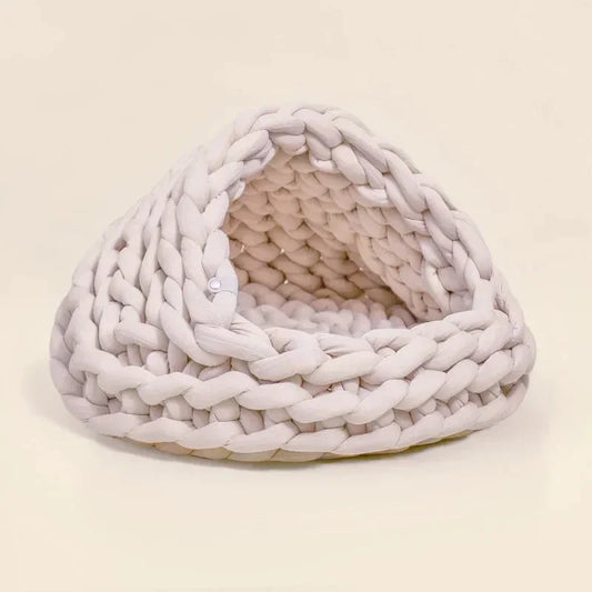 Chunky Knit Cocoon Cat Cave in ultra-thick hand-woven yarn, lower side view of the rounded knit opening, a cozy pet hideaway.