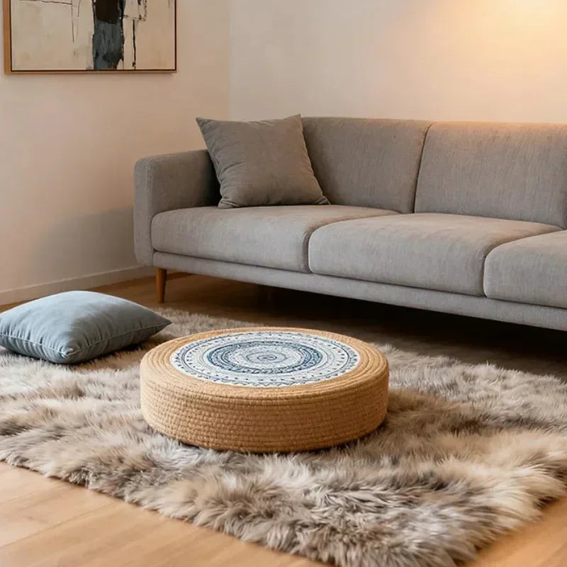 Tatami Zen Pouf in woven straw, lifestyle living room view showing detailed circular embroidery.