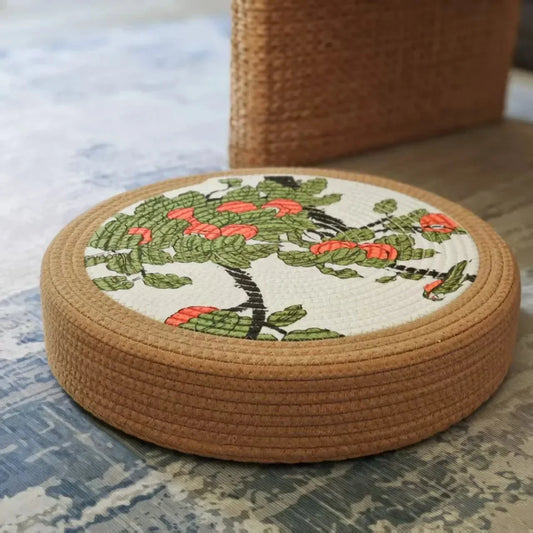 Tatami Zen Pouf in woven straw, low-angle side view of the botanical embroidered top.